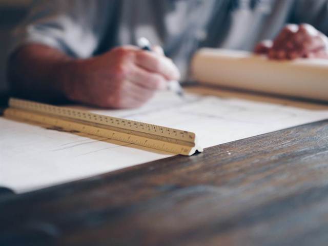 Mains traçant un plan à la règle sur une table de travail