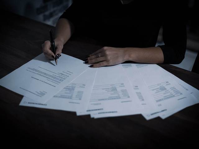 Personne annotant une série de factures étalées sur un bureau
